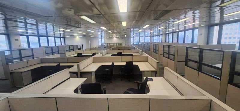 Estações de trabalho, mesas e cadeiras em escritório corporativo.